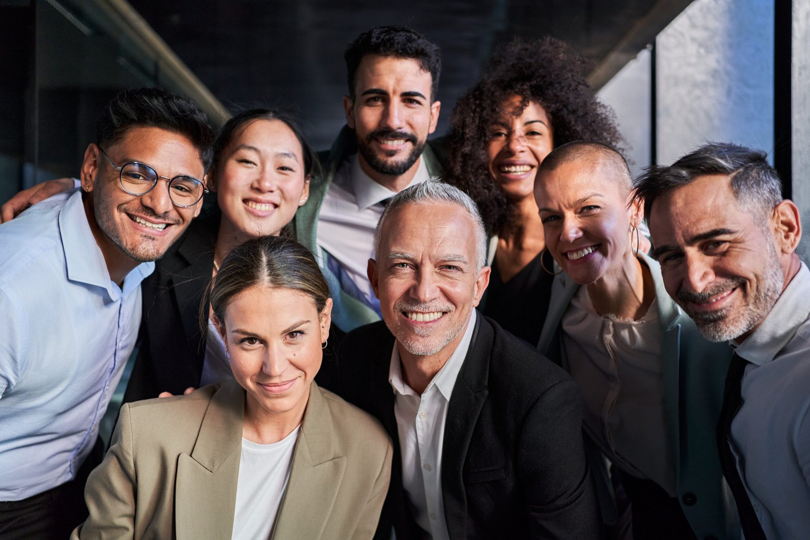 Cheerful portrait of a group of business colleagues taking a photo for the company page in the office, gathered looking at camera smiling, headed by the boss. Startup concept.